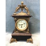 A Victorian style brass mantle clock surmounted by a leaf cast urn with bird handles, having