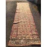 An antique bokarra runner woven with fawn field of linked paisley style motifs framed by frieze of