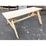 A rectangular pine garden table, the slatted plank top with hole for sunshade, on angled