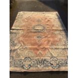 A Wilton type rug woven with floral medallion on pink field framed by scrolled frieze on blue