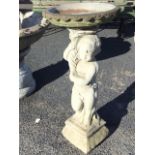 A composition stone garden birdbath, the bowl with scalloped rim supported by a draped cherub with