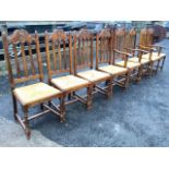 A set of eight oak Jacobean style dining chairs, the arched backs with scroll carved panels above