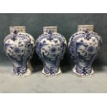 A set of three eighteenth century delft baluster shaped octagonal vases decorated with panels of