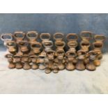 Twenty eight graduated bronze butchers weights of baluster bell shape with oval handles - several