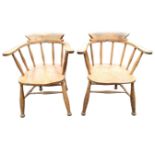 A pair of elm captains chairs, the curved smokers bow backs on spindles above solid seats, raised on