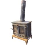 A rectangular cast iron stove with moulded top above rounded glazed panel doors with air vents
