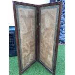 A two fold mahogany screen with leather panels framed by embossed brass borders, with brass