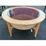 A circular 1970s walnut Schriber coffee table with glass panel to top, raised on shaped teak legs