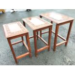 A nest of three rectangular hardwood tables carved with blind fretwork floral bands framing brass