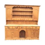 A large pine country house dresser, the back with moulded cornice and scalloped apron above open