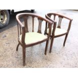 A pair of Edwardian mahogany captains style chairs, the rounded backs supported on pierced splats