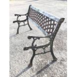 A cast iron garden bench with lattice panel to back in wood frame, having scrolled arms on