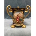 An Austrian porcelain vase with three gilt scrolled handles and burnished paw feet, decorated with