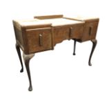 A 50s oak dressing table, the indented top flanked by rectangular rounded panels, above three