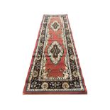 An oriental style runner, the orange field woven with two oval medallions framed by charcoal