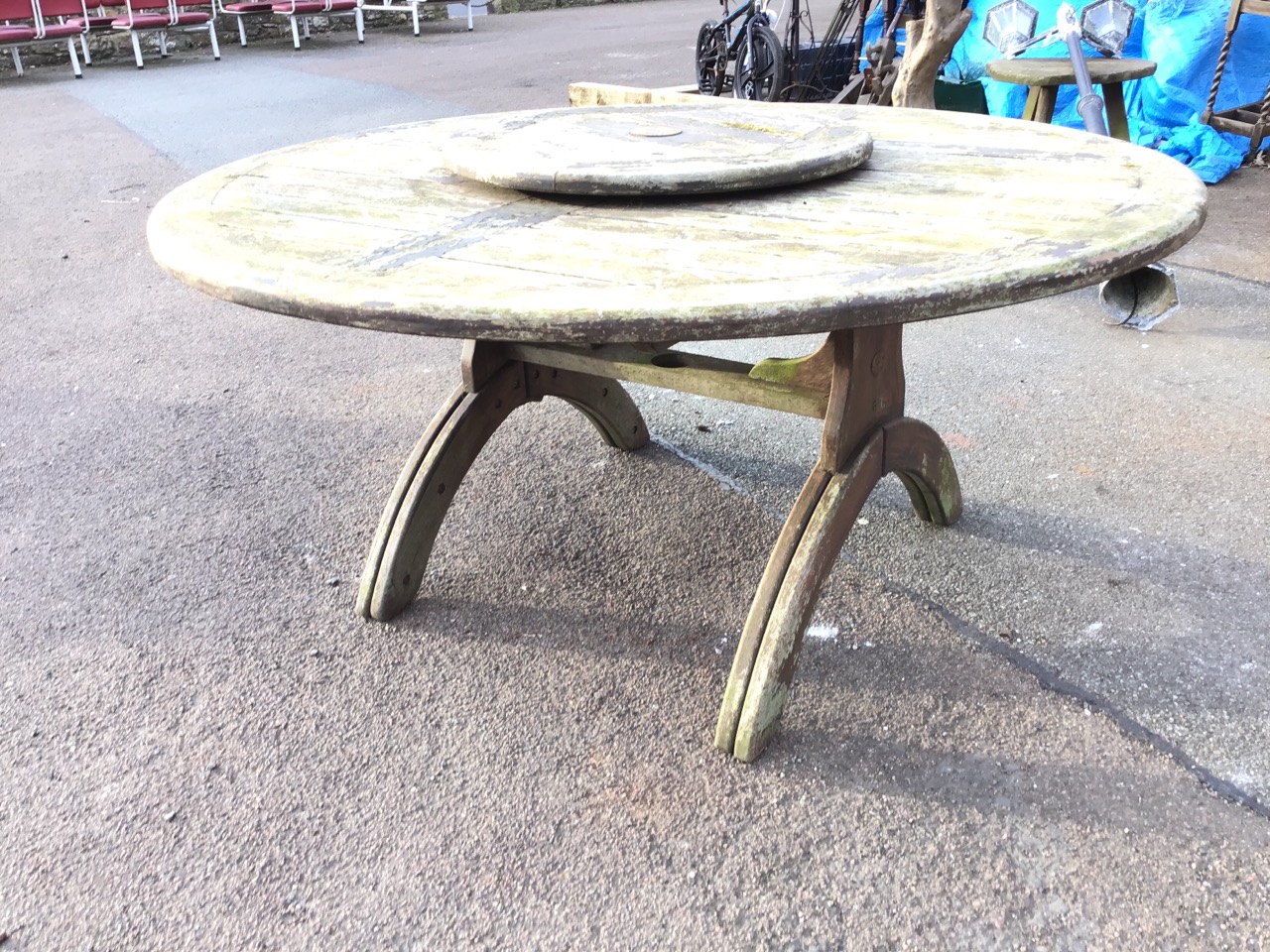 A 5ft circular teak garden table, the slatted top with central raised lazy susan, on trestle style