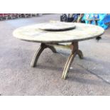 A 5ft circular teak garden table, the slatted top with central raised lazy susan, on trestle style