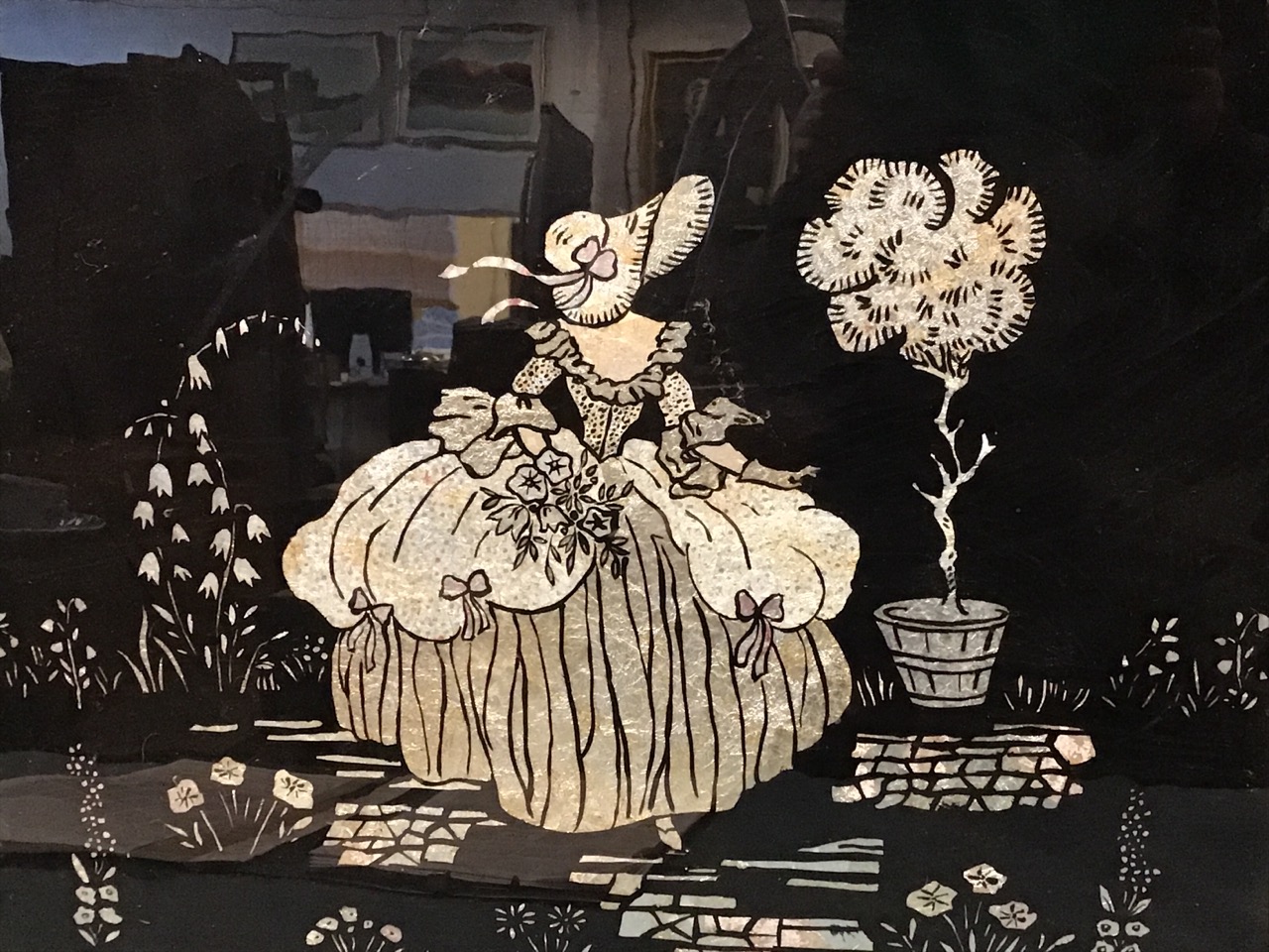 A 50s pressed silver foil silhouette picture depicting bonneted crinoline lady in garden on black