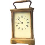 An Edwardian brass carriage clock with enamelled dial and roman chapters under bevelled glass,