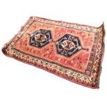 A bokarra rug woven with pair of charcoal hexagonal lozenges on red field with scrolled motifs,