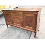 A rectangular Edwardian mahogany sideboard with raised panels to drawers and cupboards, the centre