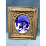 An oval blue glazed ceramic panel depicting winter scene with two children, in foliate moulded