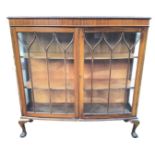 A bowfronted mahogany display cabinet with gadrooned carved moulding to top, above a plain frieze