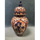 A Japanese tapering Imari vase and cover, the domed lid with dog finial, decorated in the
