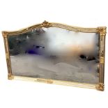A large 6ft gilt overmantle mirror, the arched frame with foliate scrolled mounts, within a twin