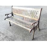 A cast iron garden bench with latticework panel to back above a slatted seat flanked by scrolled