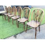 A set of six elm wheelback chairs with pierced splats flanked by spindles framed by hoops, the solid