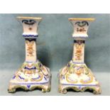 A pair of European tin glazed stoneware candlesticks, with flared urn shaped candleholders on square