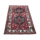 A belouchi rug woven with joined pair of serrated hexagonal medallions on red flowerhead field,