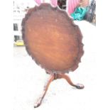 A circular Chippendale style tilt-top mahogany coffee table, the scalloped tray top on gadrooned