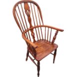 A nineteenth century elm windsor chair with hooped back on spindles framing pierced shaped splat,