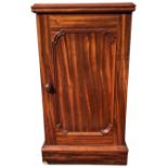 A Victorian mahogany bedside pot cupboard with moulded top and rounded panelled door enclosing a