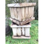 A pair of large square wood garden planters with plank sides and mesh bases, raised on battens. (