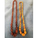 A set of Edwardian graduated amber beads; and another similar set of paler oval beads. (2)