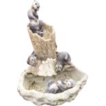 A composition stone garden water feature modelled with four otters on logs above a tree-trunk