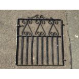 A wrought iron garden gate with scrolled decoration to rectangular frame, having panel of square