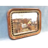 A late Victorian mirror in rectangular rounded cushion moulded faux walnut frame, with gilt slip and