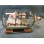 A ship in a bottle, the gallon flagon with twin rings to neck, corked and containing a two mast