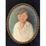 An early C20th oval pastel portrait of a young boy, signed indistinctly in pencil, in leaf moulded