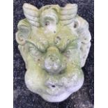 A composition stone garden wall waterspout gargoyle modelled as a horned blowing head. (10.5in)