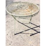 A circular wrought iron folding garden table with scrolled medallion to radiating slatted top, the