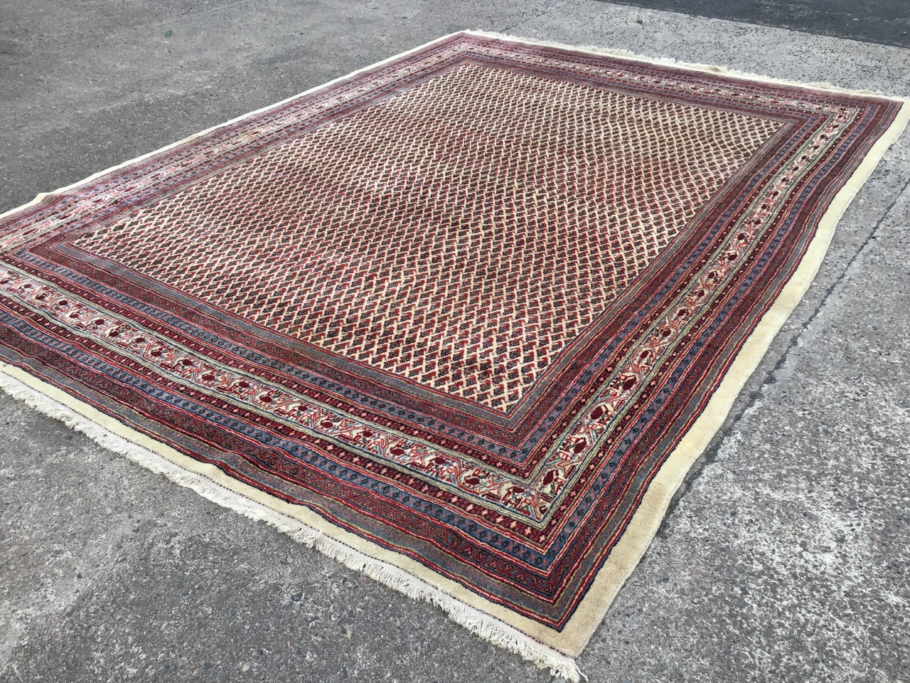 An Iranian carpet woven in the Arak style with fawn field of floral lozenges framed by multiple