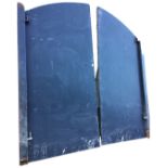 A pair of painted arched galvanised metal doors on square metal frames, fitted with closing bolts