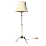 A Victorian brass adjustable standard lamp and shade with extending pole, raised on tripod legs with