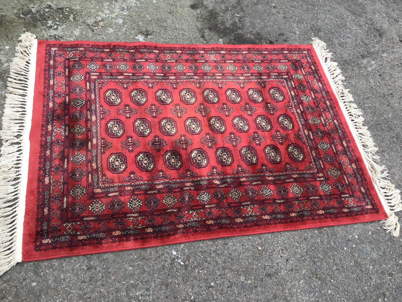 A bokarra rug woven with red field of octagonal lozenges and hooked battens within a wide border