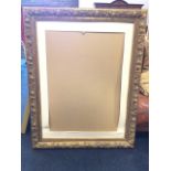 A large empty gilt picture frame with fruit & floral moulding within a beaded border, the inner band
